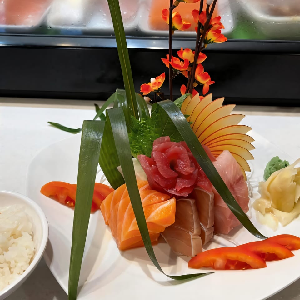 A vibrant sashimi platter with salmon, tuna, and yellowtail, garnished with apple slices and greens.